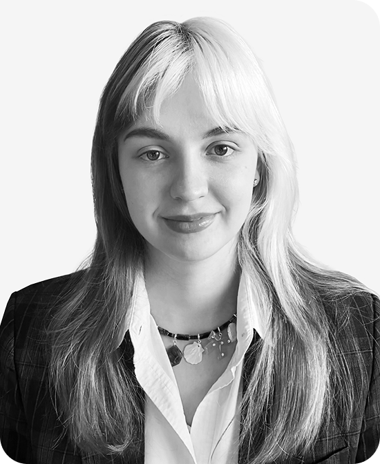 Headshot of a young woman with light hair wearing a blazer and necklace, smiling softly.