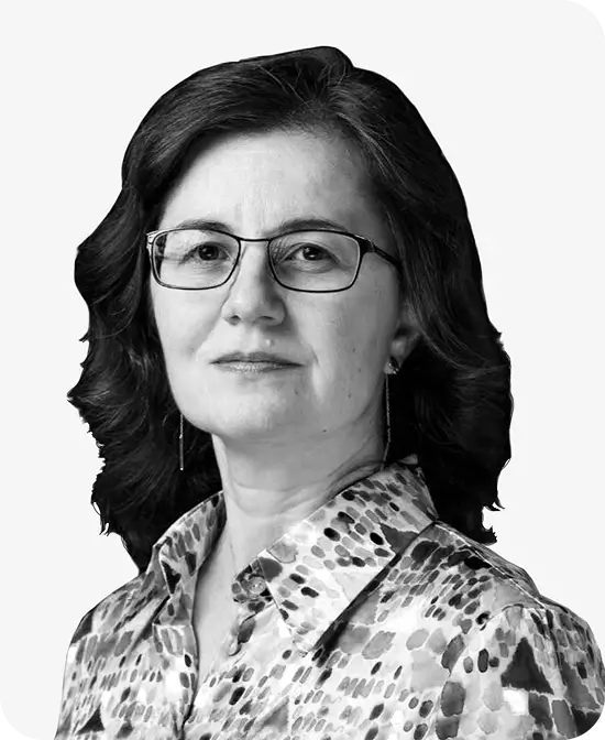 Portrait of a mature professional woman wearing glasses and a patterned blouse.